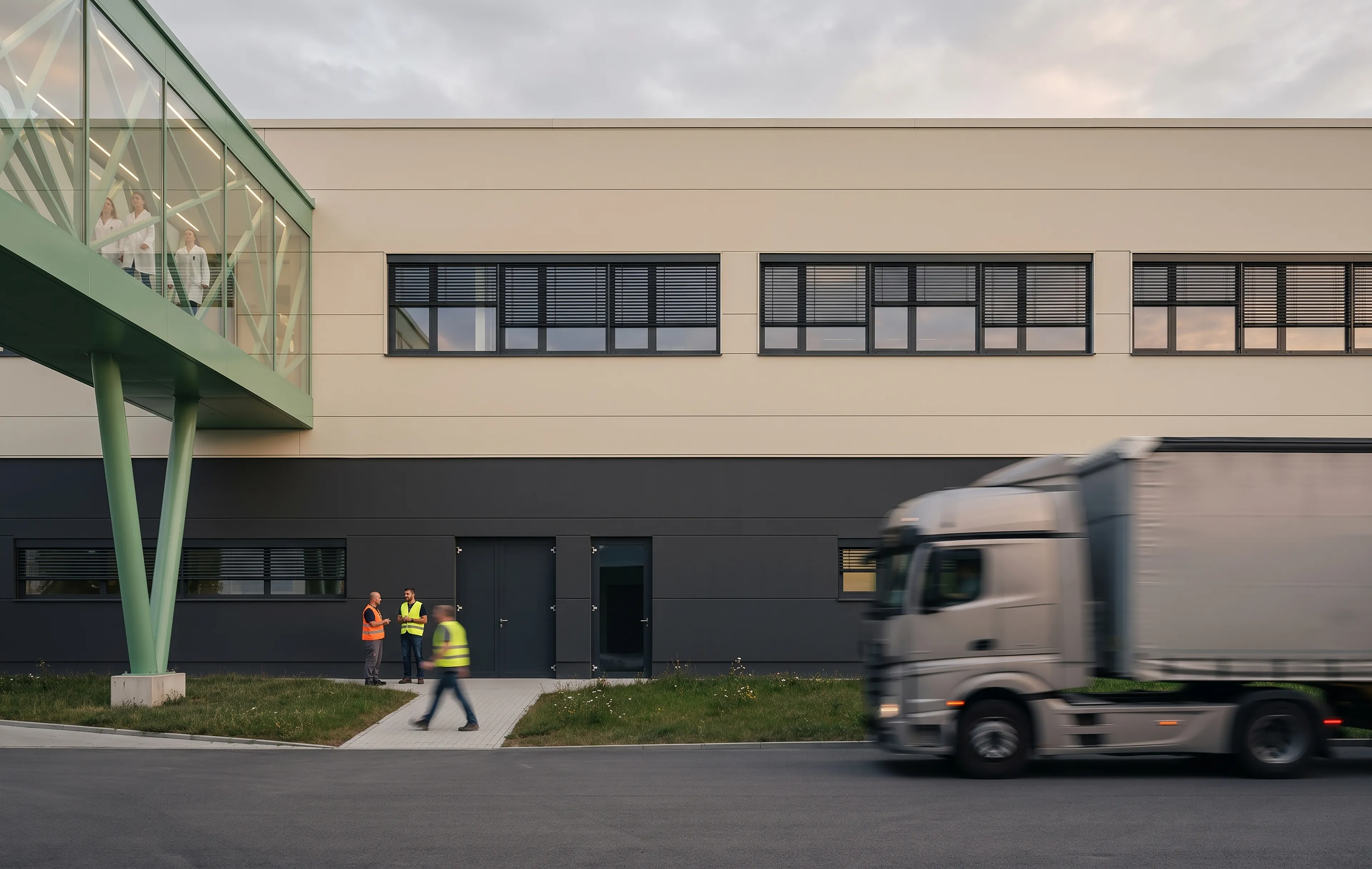 Pracovní ruch pod proskleným mostem v industriálním areálu